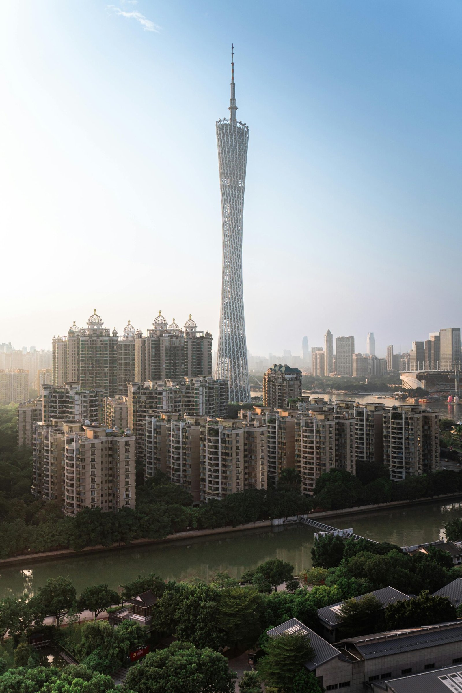 A stunning view of Canton Tower amidst Guangzhou's skyline with residential buildings and a river below.